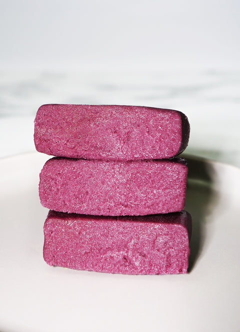 Stacked pieces of Lemke Very Cherry marzipan with pink cherry almond filling on a white plate