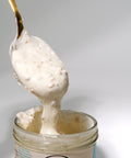 Creamy Lemke Stadtstreicher Kokos-Mandel Crunchy coconut almond spread on a spoon from an open jar