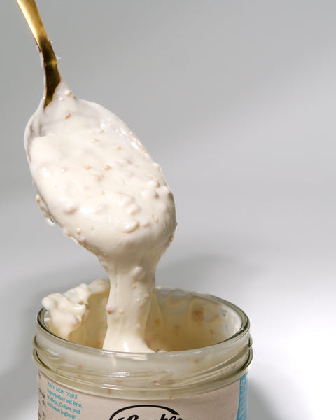 Creamy Lemke Stadtstreicher Kokos-Mandel Crunchy coconut almond spread on a spoon from an open jar