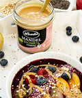Lemke Mandelcreme Bioprodukt auf einer Smoothie Bowl mit frischen Früchten, Beeren und Chiasamen, auf einem weißen Tablett serviert.