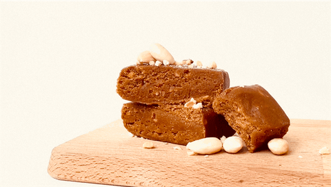 Mehrere gestapelte Lemke Salty Caramel Marzipan-Riegel, garniert mit Mandelstückchen. Einer der Riegel ist angebrochen, sodass die weiche, karamellfarbene Füllung sichtbar wird